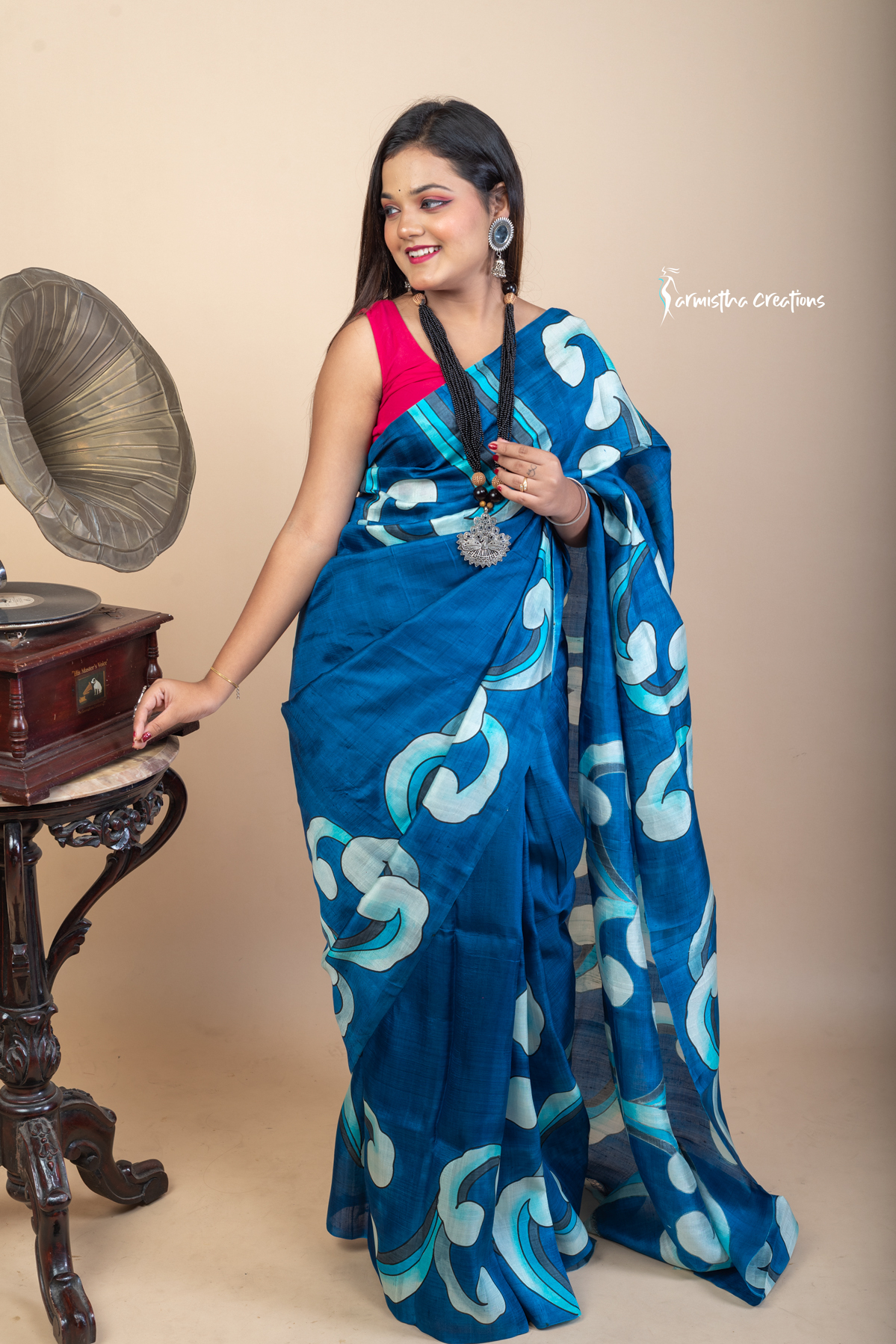 Bold and fluid like waves, this hand painted Bishnupuri silk saree features aqua and ivory motifs on an ocean blue base. Crafted from pure Bengal silk, it’s a lightweight, striking drape for standout moments.