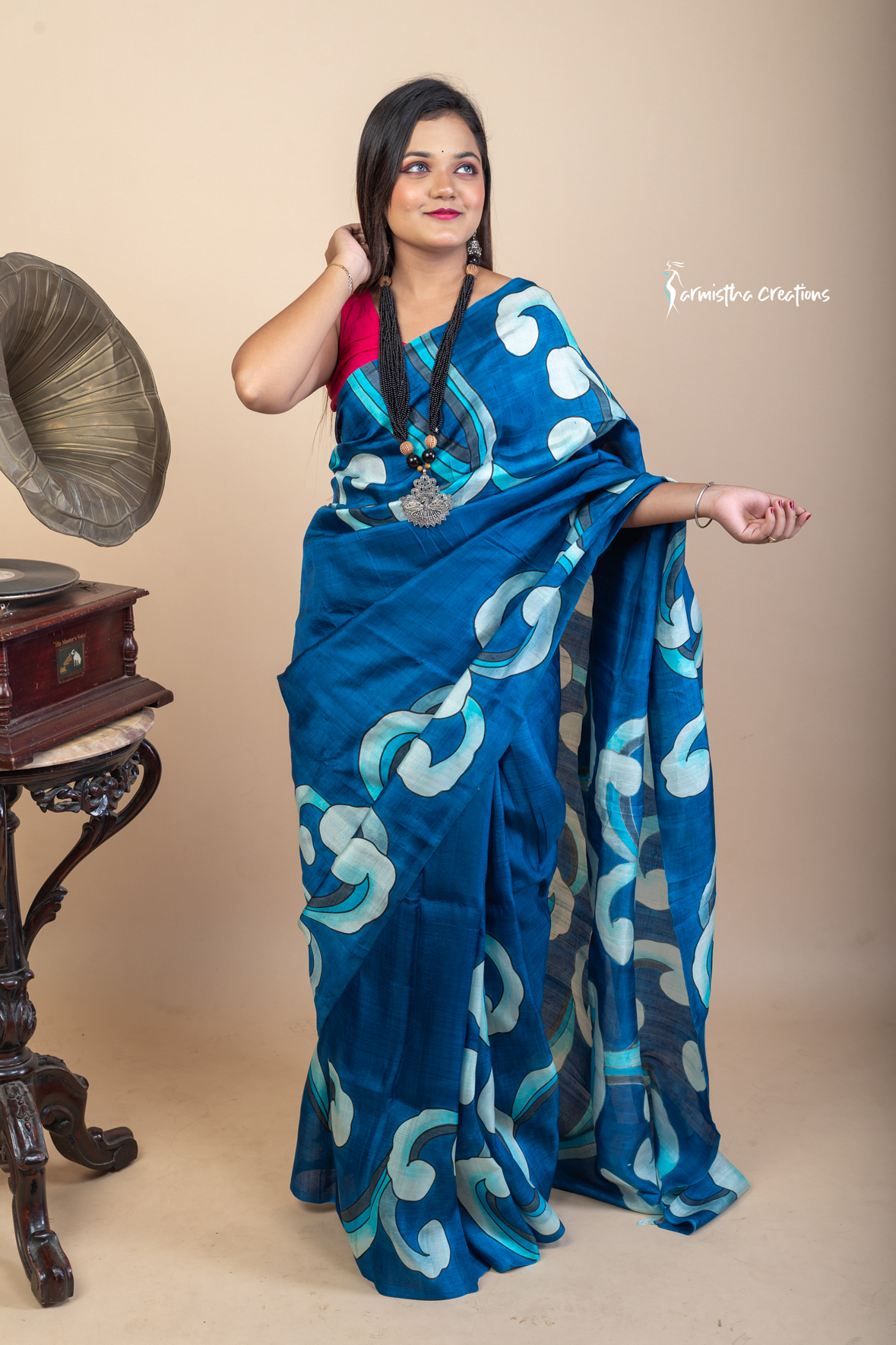 Bold and fluid like waves, this hand painted Bishnupuri silk saree features aqua and ivory motifs on an ocean blue base. Crafted from pure Bengal silk, it’s a lightweight, striking drape for standout moments.