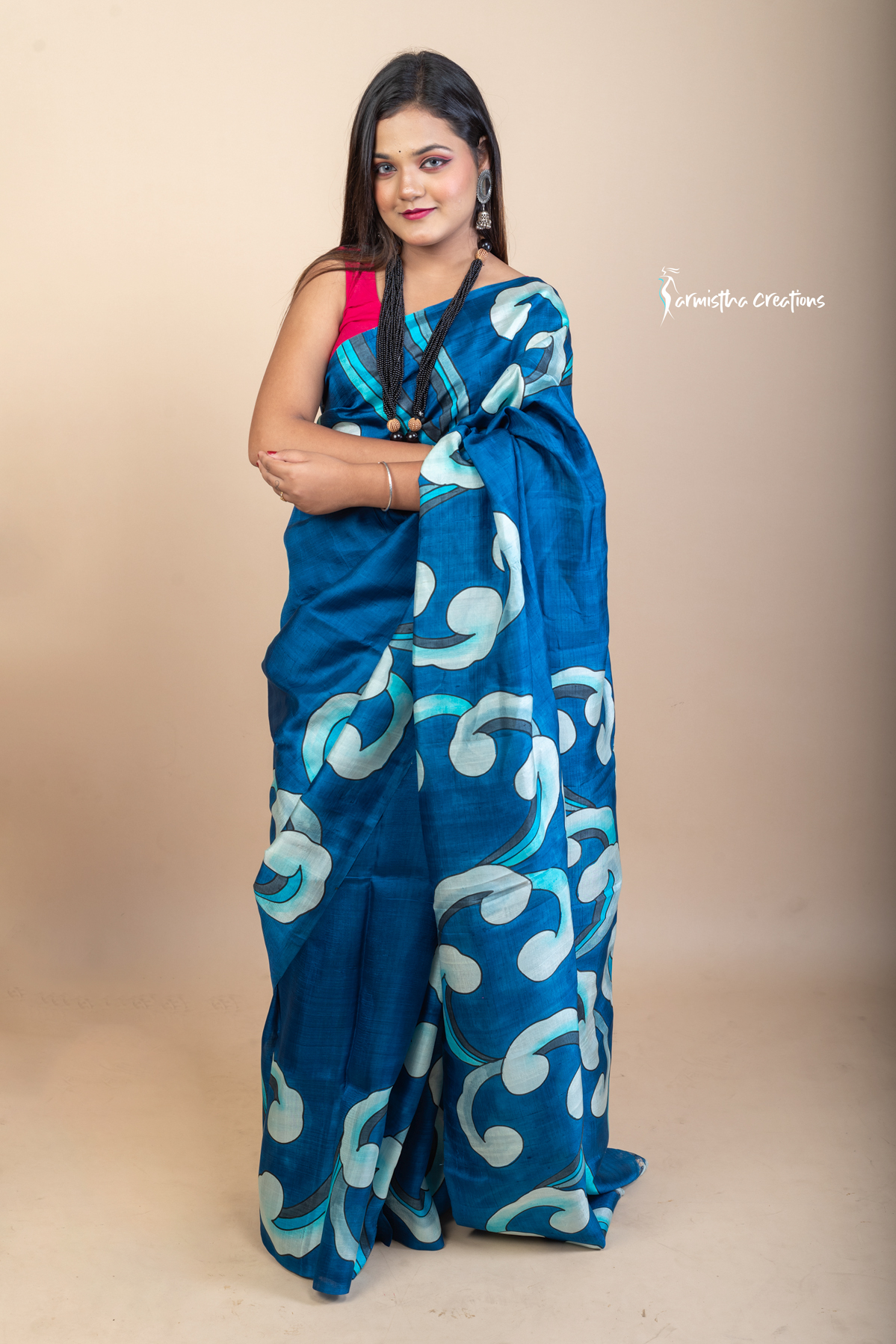 Bold and fluid like waves, this hand painted Bishnupuri silk saree features aqua and ivory motifs on an ocean blue base. Crafted from pure Bengal silk, it’s a lightweight, striking drape for standout moments.