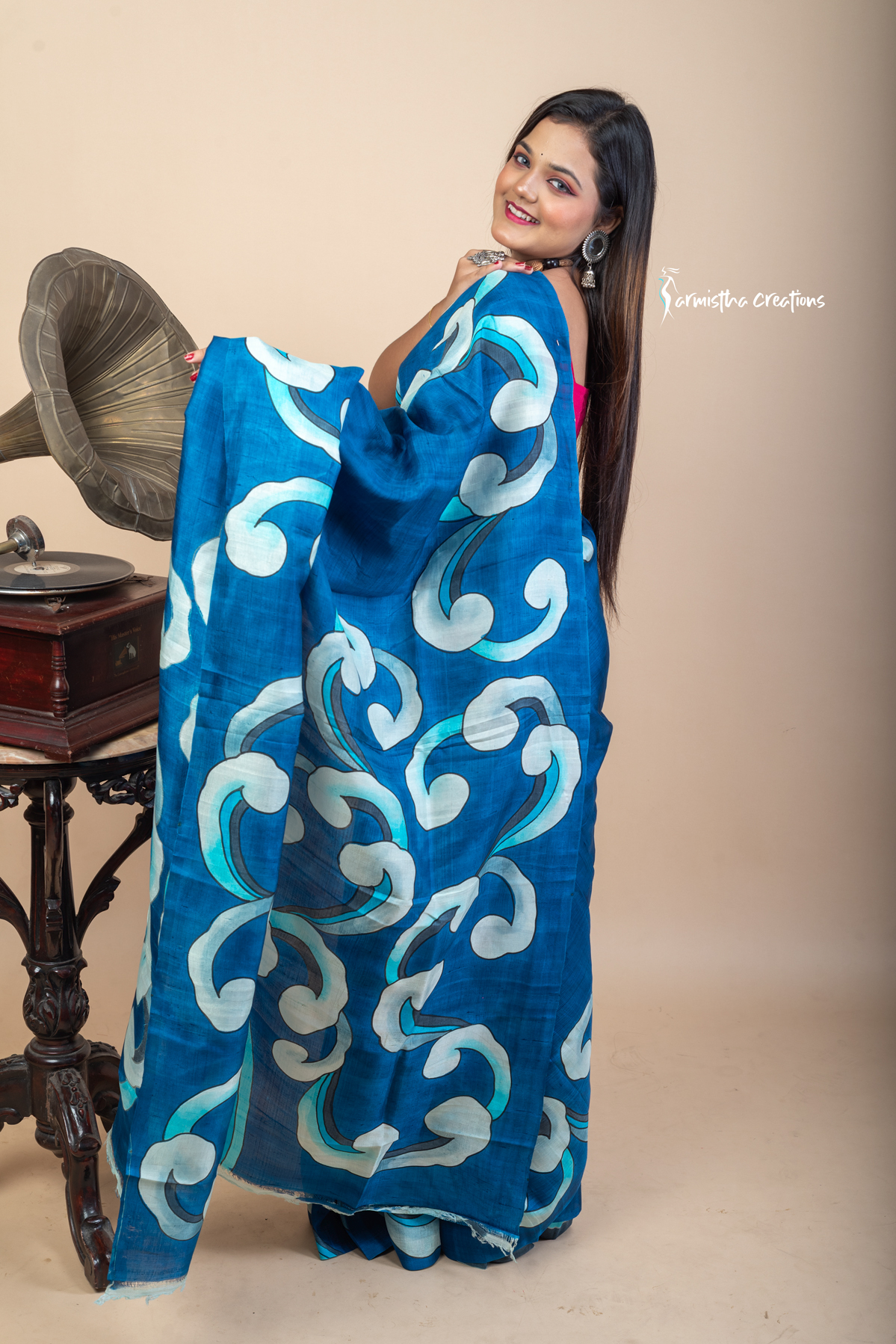 Bold and fluid like waves, this hand painted Bishnupuri silk saree features aqua and ivory motifs on an ocean blue base. Crafted from pure Bengal silk, it’s a lightweight, striking drape for standout moments.