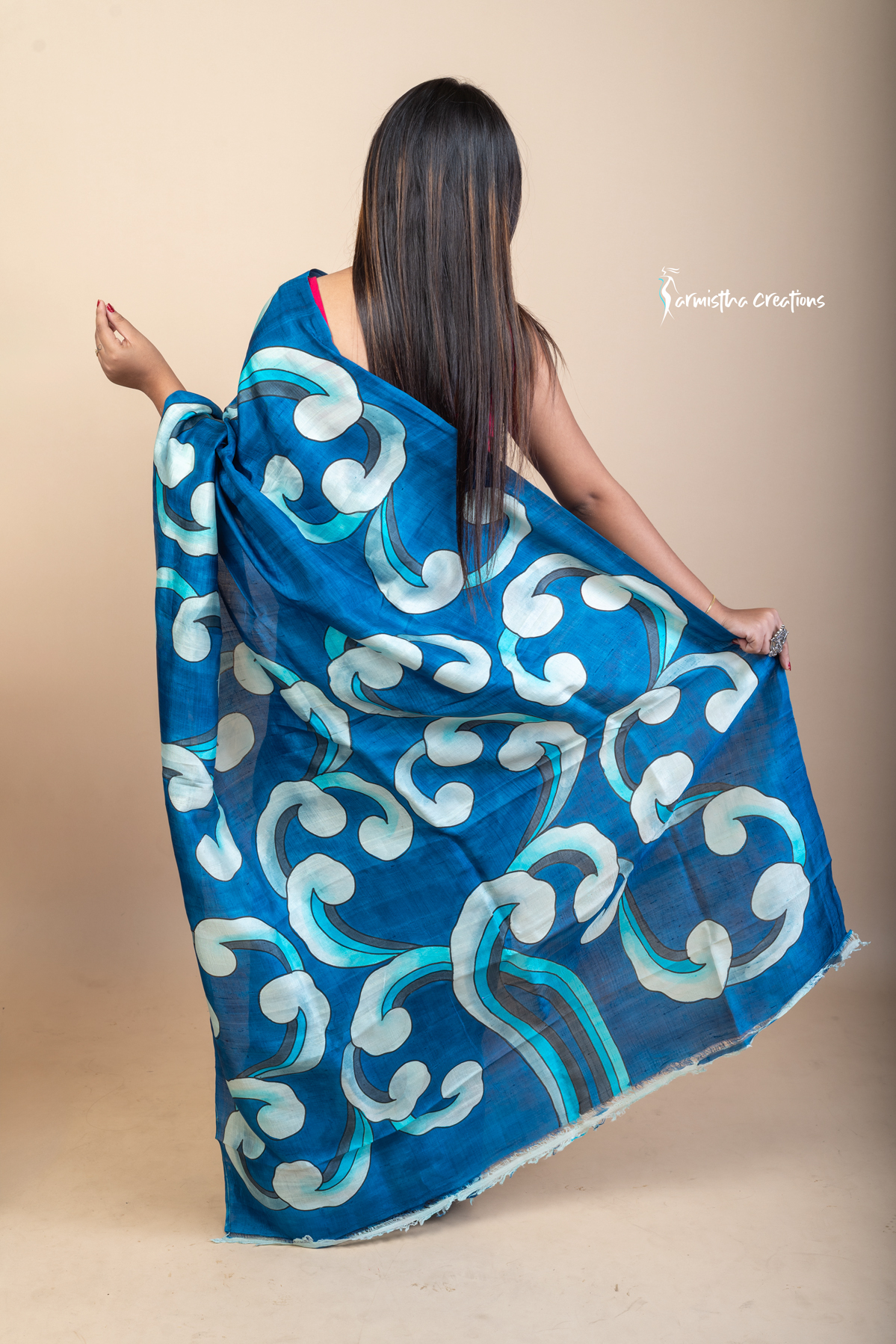 Bold and fluid like waves, this hand painted Bishnupuri silk saree features aqua and ivory motifs on an ocean blue base. Crafted from pure Bengal silk, it’s a lightweight, striking drape for standout moments.