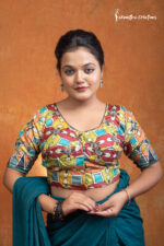 Rangashree is a hand kalamkari ready-stitched blouse that celebrates the festive spirit of colors. Adorned with bold floral and geometric kalamkari motifs in hues of red, mustard, teal, and orange, this blouse radiates vibrancy and charm.