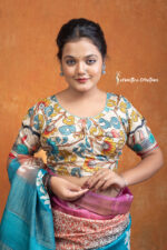 Charulata is a hand kalamkari ready-stitched blouse that embodies natural elegance. Featuring delicate floral vines and motifs in soothing tones of teal, mustard, and earthy hues on a cream base, this blouse carries the charm of handcrafted artistry.