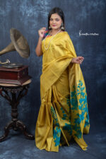 Woven from 100% tussar silk with no zari border, Aabhaa glows in a radiant mustard-yellow hue with hand-painted floral artistry. Lightweight, naturally lustrous, and full of graceful sheen—an ode to quiet elegance.