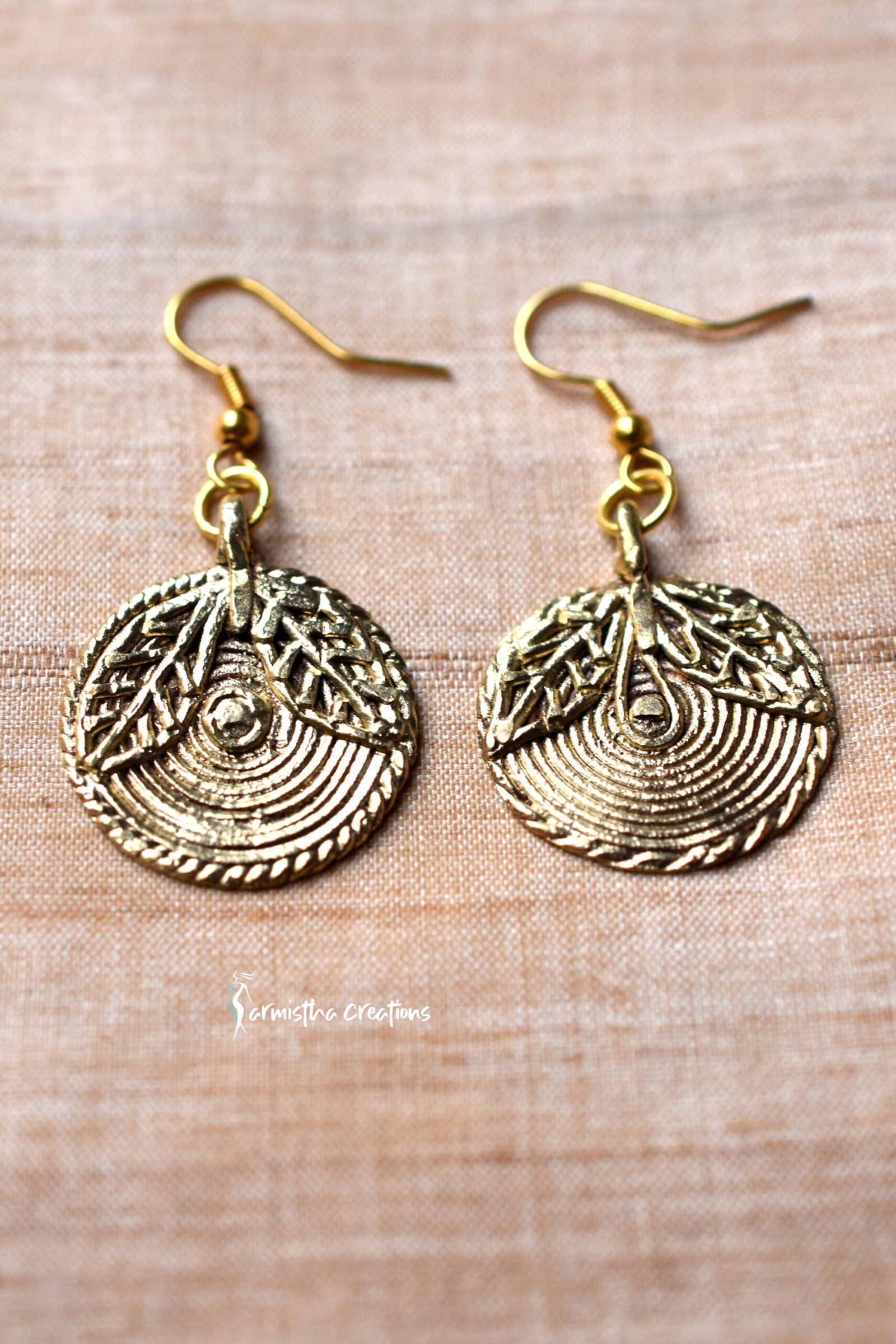 Tribal dokra earrings featuring a textured, circular design with leaf motifs