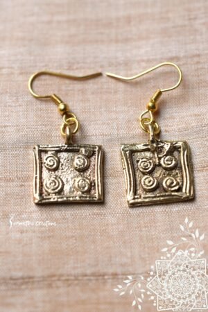 Tribal dokra earrings featuring square charms with a spiral embossed design.